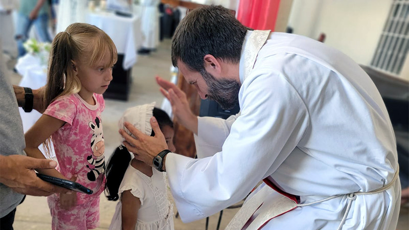 Photo of a priest blessing two young girls